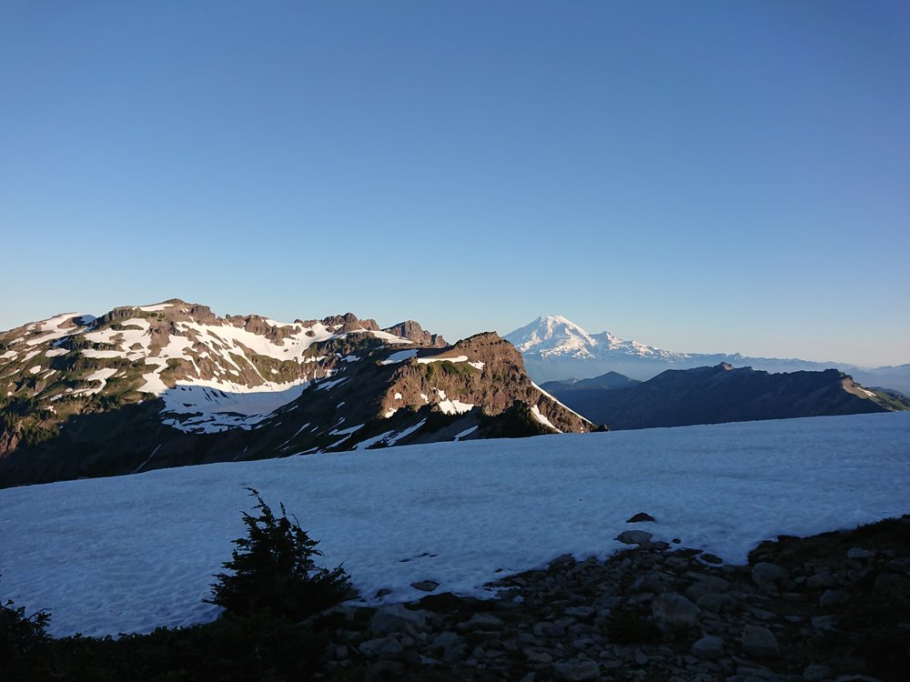  Mount Rainier in distance with a snow covered high mountain lake in the foreground 